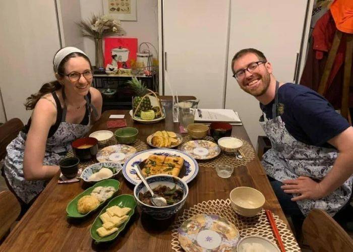 A Kyoto cooking class in which two guests are smiling by their handmade teriyaki chicken meal.